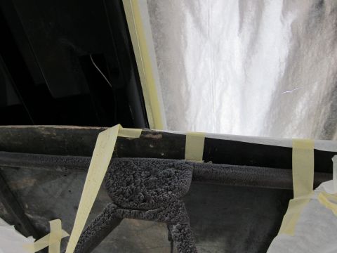 1987 Dodge 1500 - A close-up view of a vehicle's undercarriage part, covered in a textured coating and taped off.