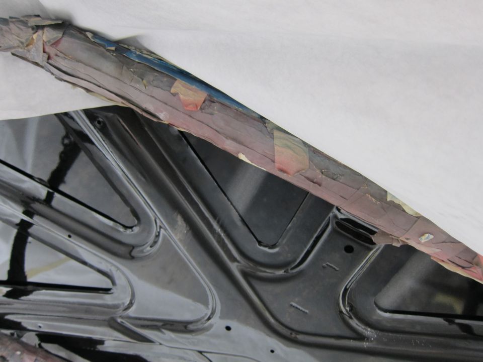 Underside of black car hood with taped edge