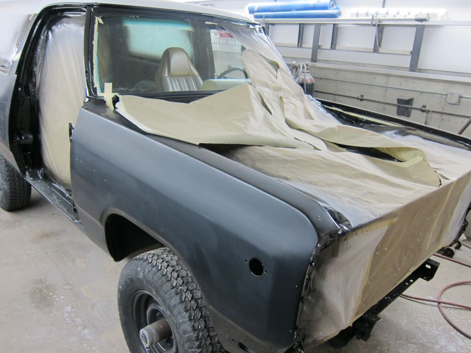 Truck in a workshop, covered in masking paper for paint prep. Door and fender are exposed