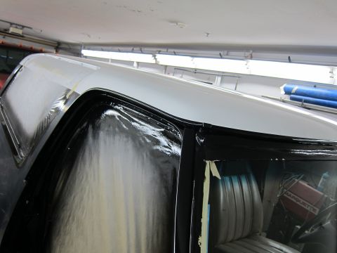 1987 Dodge 1500 - Detail of a truck cab undergoing bodywork, showing the black trim and white roof being painted.