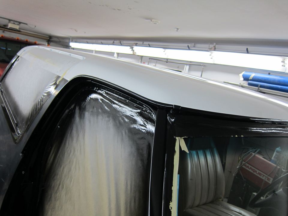 Truck cab with black trim and white roof during paintwork. Interior visible