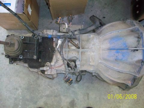 2000 Isuzu Vehicross - Transmission assembly shown on a concrete floor with boxes in the background.