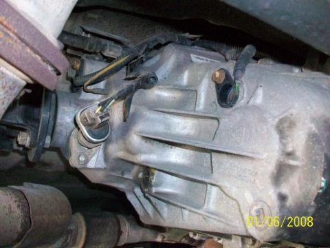 2000 Isuzu Vehicross - This photo shows the underside of a vehicle's transmission, focusing on the gearbox casing and attached electrical components.