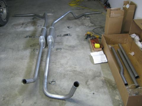 1979 Ford Bronco - Exhaust system components are arranged on the floor, ready for installation.