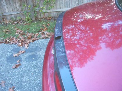 1997 Ford Taurus - Close-up of a red car's trunk area, showing reflections and a website logo.
