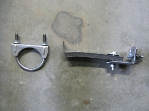 1979 Ford Bronco - Two separate exhaust system mounting components are laid out on a concrete surface.