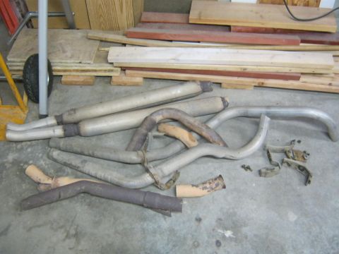 1979 Ford Bronco - A collection of exhaust system components, including pipes and mufflers, are shown on a workshop floor.