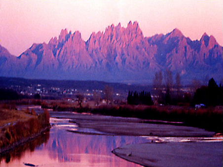 1995 Ford Bronco - A scenic landscape with mountains, a river, and a distant town under a pink and purple sky.