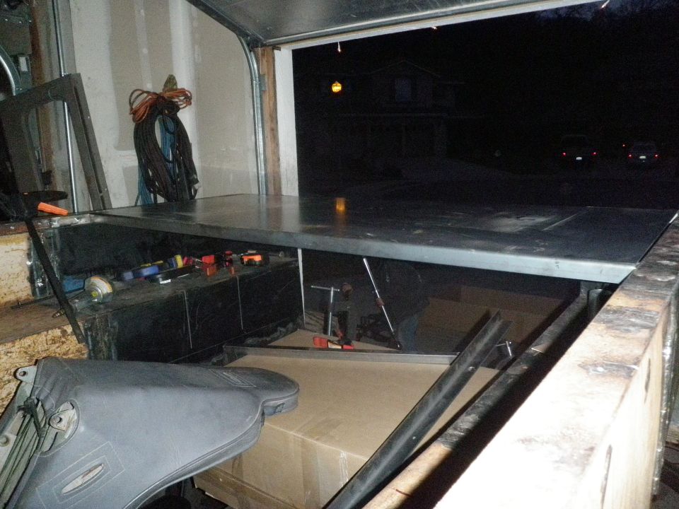 Truck cab interior at night showing seat removed and dash apart in garage