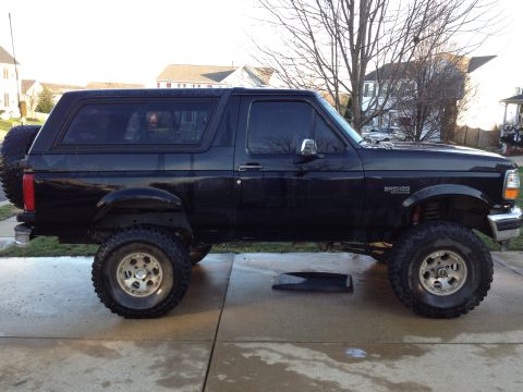 1995 Ford Bronco - This black Ford Bronco is shown from the side, a lifted suspension and large off-road tires.