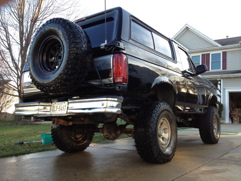 1995 Ford Bronco - This black Ford Bronco is shown from a rear three-quarter view, lifted with off-road tires.