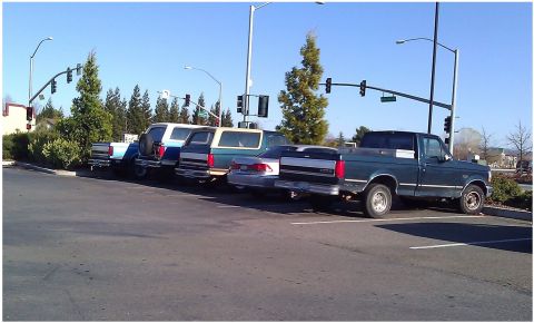 1992 Ford F-150 - A row of vehicles, including a 1992 Ford F-150, are parked in a lot under a clear blue sky.