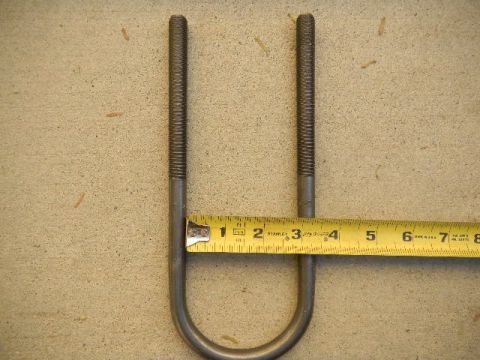 1997 Ford Ranger - A U-bolt is measured with a tape measure, indicating its size for potential vehicle part replacement.