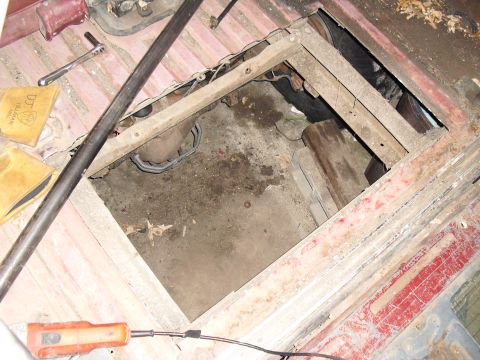 1986 Ford Bronco - A view into the floor of a vehicle, showing exposed mechanical parts and signs of wear.