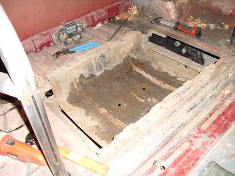 1986 Ford Bronco - The interior floor pan shows significant rust and is in need of repair, with tools scattered around.