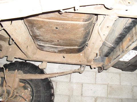 1986 Ford Bronco - Undercarriage view reveals fuel tank and suspension components of an older vehicle.
