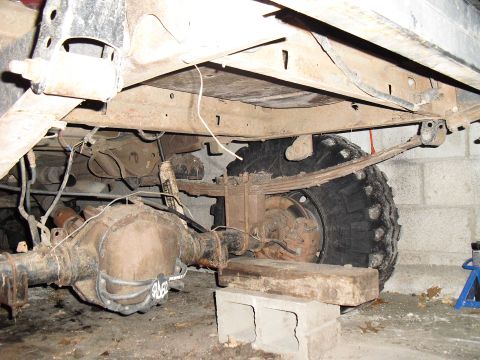 1986 Ford Bronco - The underside of a vehicle is shown, with a focus on the rear axle and suspension components.