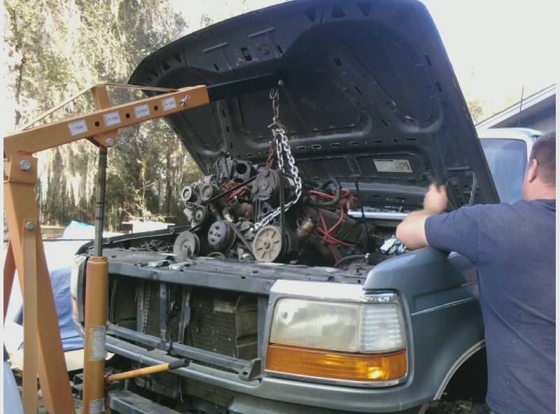 Engine being lifted out of a 1995 Ford Bronco with an engine hoist