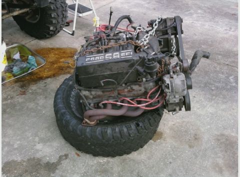 1995 Ford Bronco - A Ford 5.8 EFI engine is shown resting on a large tire, secured with chains.