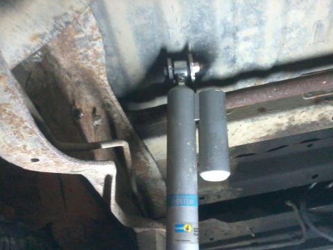 1995 Ford Bronco - Close-up view of a vehicle's rear shock absorber assembly, showing the Bilstein brand and rusty undercarriage parts.