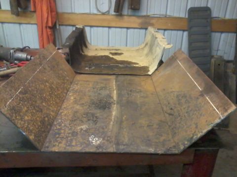 1995 Ford Bronco - Metal skid plate shown on a workbench in a garage setting.