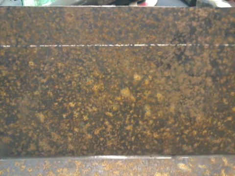 1995 Ford Bronco - A close-up view of a heavily rusted metal skid plate, showing signs of wear and tear.