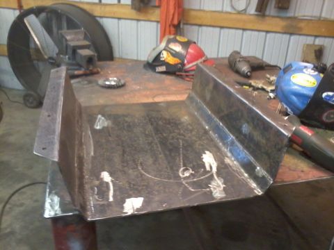 1995 Ford Bronco - A metal skid plate is shown on a workbench, with various tools and welding helmets in the background.