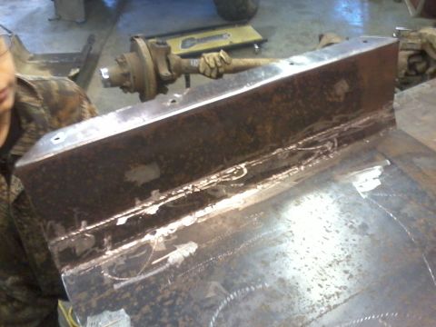 1995 Ford Bronco - A close-up view of a gas tank skid plate, showing welding work and an attached hub assembly.