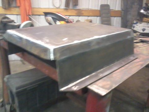1995 Ford Bronco - A fabricated metal skid plate rests on a workbench, indicating it is a vehicle part.