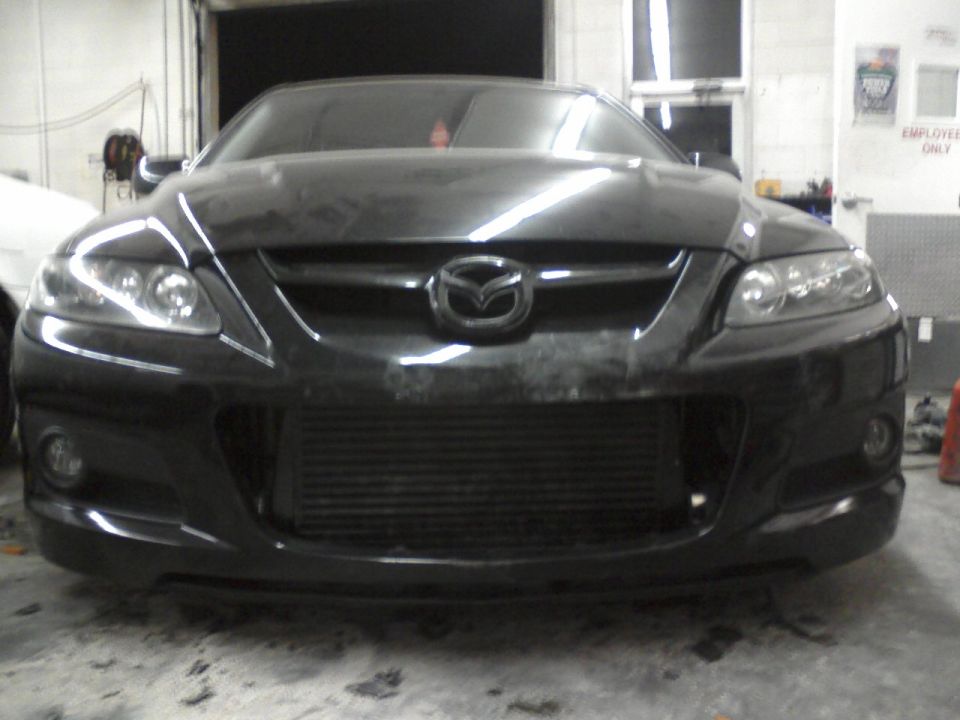 Black Mazda 6 front bumper with large intercooler visible behind grille. Mazda logo on hood