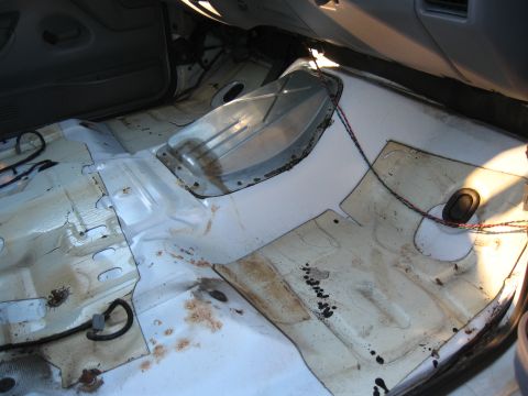 1994 Ford Bronco - The bare metal floor of a vehicle interior is visible after the carpet has been removed.