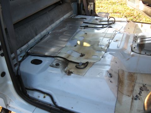 1994 Ford Bronco - Vehicle interior floor after carpet removal, revealing exposed metal and wiring.