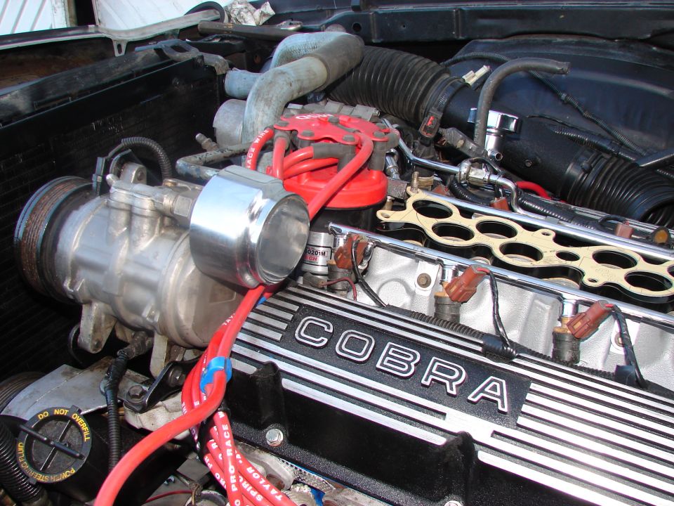 Engine with "COBRA" valve cover, red spark plug wires, and air conditioning compressor