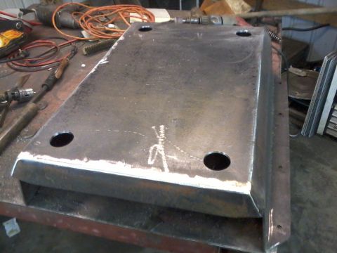 1995 Ford Bronco - A fabricated metal skid plate rests on a workbench, surrounded by tools and electrical cords.