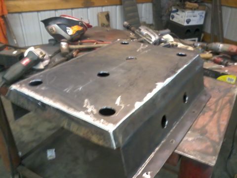 1995 Ford Bronco - A metal skid plate with several circular holes is shown on a workbench, surrounded by tools.