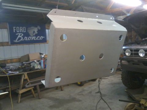 1995 Ford Bronco - A silver skid plate is shown hanging in a garage, with a vehicle partially visible in the background.