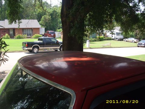 1990 Ford F-150 - A black Ford F-250 Super Duty pickup truck is parked on a residential street, with another vehicle in the foreground.