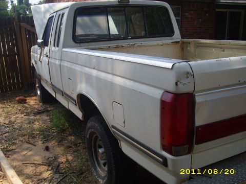 1990 Ford F-150 - A white 1990 Ford F-150 pickup truck is parked outdoors with its hood up, showing its rear three-quarter view.