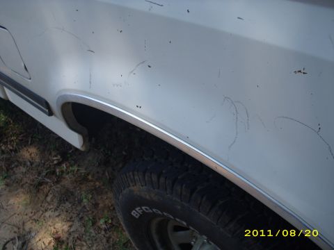1990 Ford F-150 - Close-up view of the side of a white 1990 Ford F-150, showing the fender and wheel.