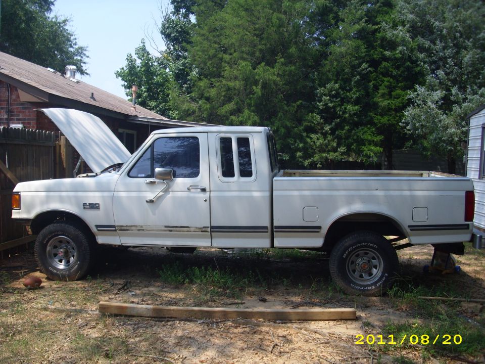 White 1990 Ford F-150 extended cab pickup truck parked outside with hood up