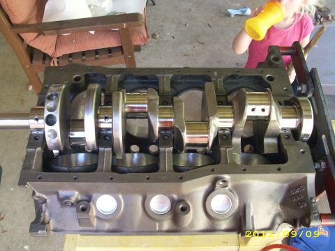 1990 Ford F-150 - Close-up of a vehicle's engine block and crankshaft assembly, with a child in the background.