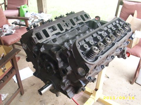 1990 Ford F-150 - A disassembled engine block is shown on a stand, with various items scattered on chairs in the background.