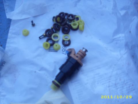 1990 Ford F-150 - A fuel injector and a pile of assorted seals and O-rings are laid out on a white surface.