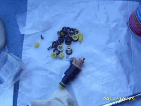 1990 Ford F-150 - A close-up view of a fuel injector and its associated seals, laid out on a white cloth.