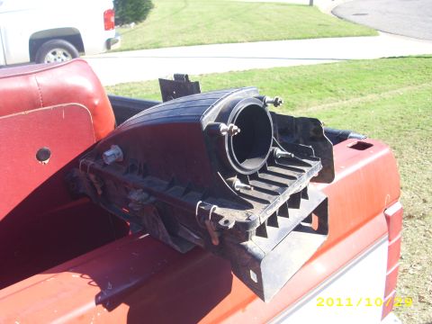1990 Ford F-150 - An air intake component is visible in the bed of a red pickup truck, with a white truck in the background.