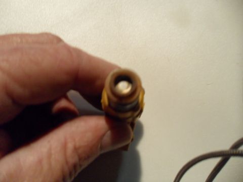 1973 Ford Ranchero - A hand holds a spark plug, showing its internal components.