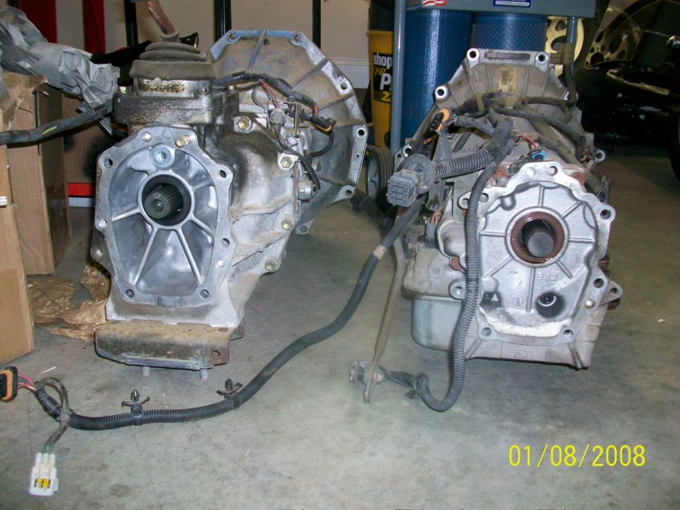 Two vehicle transmissions are shown side-by-side on a concrete floor