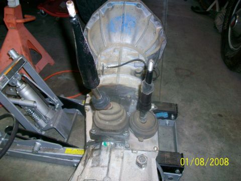 2000 Isuzu Vehicross - Transmission and transfer case assembly with two shifter levers, on a shop floor. Date stamp 01/08/2008.