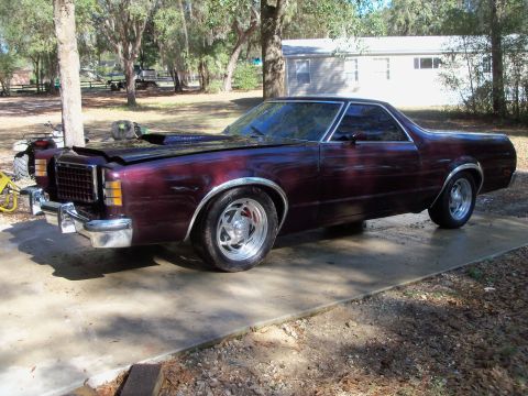 1979 Ford Ranchero - Three-quarter front view of a dark maroon Ford Ranchero coupe-utility parked on a concrete driveway in a wooded rural setting. It has polis…