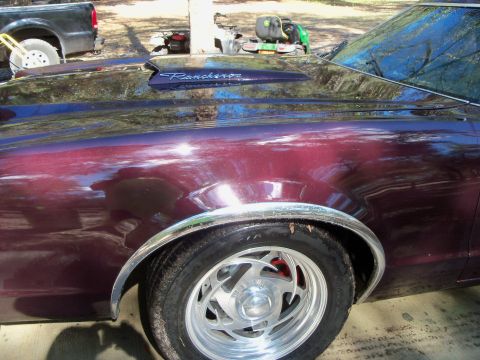 1979 Ford Ranchero - Tight rear-quarter view of a dark maroon Ford Ranchero showing the chrome "Ranchero" script badge on the bedside, chrome fender-lip trim an…